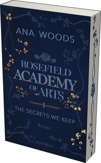Das Buchcover zeigt einen tiefblauen Hintergrund, der mit filigranen floralen Mustern in Creme und Gold verziert ist. Oben befindet sich der Autorname „ANA WOODS“ in hellem, eleganten Schriftzug. In der Mitte ist der Titel „ROSEFIELD ACADEMY of ARTS“ in markanter, größerer Schrift dargestellt, darunter der Untertitel „THE SECRETS WE KEEP“ in kleinerer, aber ebenfalls gut lesbarer Schrift. Am unteren Rand steht das Wort „Roman“ in schlichtem Font. Die Atmosphäre des Covers vermittelt ein geheimnisvolles und künstlerisches Ambiente.