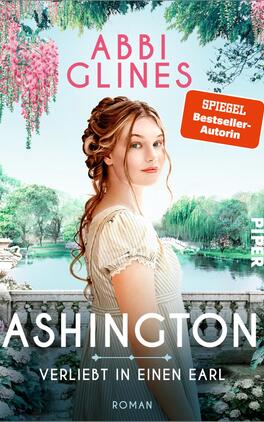 Das Buchcover zeigt eine junge Frau mit langen, gewellten Haaren, die in einem romantischen Garten steht. Sie trägt ein helles, schlichtes Kleid und blickt direkt in die Kamera. Im Hintergrund sind üppige Pflanzen und blühende Bäume zu sehen, die eine idyllische Atmosphäre schaffen. Der Titel „ASHINGTON – Verliebt in einen Earl“ erscheint in großen, weißen Buchstaben am unteren Rand. Oben steht „ABBI GLINES“ in rosa und der Hinweis „SPIEGEL Bestseller-Autorin“ in einer orangefarbenen Box.