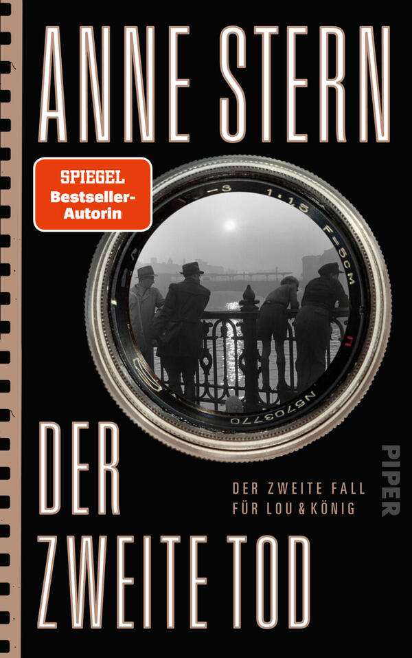 Das Buchcover zeigt den Namen der Autorin Anne Stern in großen, schmalen, hellbeigen Versalien über einem schwarzen Hintergrund, darunter der Titel „Der zweite Tod“ in gleicher Typografie. Zentral ein silberner Kameraring mit einer schwarz-weiß-Fotografie: Silhouetten von Menschen an einem Brückengeländer im Nebel. Links eine beigefarbene Spiralrand-Illustration, oben links ein orangefarbener Button mit der Aufschrift „SPIEGEL Bestseller-Autorin“. Stimmung düster und noirhaft.