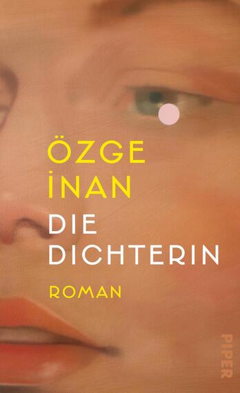Das Buchcover zeigt ein weichgezeichnetes Nahaufnahmeporträt in warmen Pfirsich‑ und Sandtönen, links mittig der Autorenname „ÖZGE İNAN“ in leuchtendem Gelb, darunter der Titel „DIE DICHTERIN“ in weißen Großbuchstaben und weiter unten „ROMAN“ in kleiner gelber Schrift. Ein kleiner rosa Punkt über dem Auge setzt einen Akzent. Die Gestaltung wirkt nah, ruhig und träumerisch.