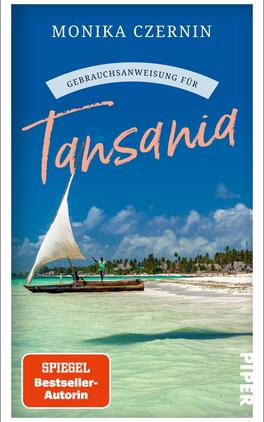 Das Buchcover zeigt eine malerische Küstenlandschaft mit klarblauem Wasser und einem Segelboot, das im Vordergrund fährt. Im Hintergrund sind sanfte, grüne Hügel und ein blauer Himmel mit einigen Wolken sichtbar. Der Titel „Gebrauchsanweisung für Tansania“ ist in einer handschriftlichen, orangefarbenen Schriftart platziert, während „MONIKA CZERNIN“ in einer klaren, serifenlosen Schrift darüber steht. In der unteren rechten Ecke befindet sich ein rotes Kästchen mit dem Text „SPIEGEL Bestseller-Autorin“.