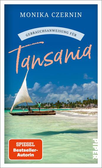 Das Buchcover zeigt eine malerische Küstenlandschaft mit klarblauem Wasser und einem Segelboot, das im Vordergrund fährt. Im Hintergrund sind sanfte, grüne Hügel und ein blauer Himmel mit einigen Wolken sichtbar. Der Titel „Gebrauchsanweisung für Tansania“ ist in einer handschriftlichen, orangefarbenen Schriftart platziert, während „MONIKA CZERNIN“ in einer klaren, serifenlosen Schrift darüber steht. In der unteren rechten Ecke befindet sich ein rotes Kästchen mit dem Text „SPIEGEL Bestseller-Autorin“.