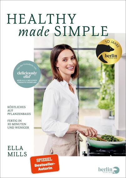 Das Buchcover zeigt eine freundliche Frau, die in einer hellen Küche steht und mit einem Kochlöffel in einer Pfanne rührt. Der Hintergrund ist teilweise durch große Fenster hell erleuchtet. Der Titel „HEALTHY made SIMPLE“ ist in eleganter, grüner Schrift oben platziert, während „made SIMPLE“ in einer abweichenden Schriftart betont wird. Unten steht der Name „ELLA MILLS“ in großer, klarer Schrift. Zudem sind die Hinweise „Köstliches auf Pflanzenbasis“ und „Fertig in 30 Minuten und weniger“ in kleinerer Schrift zu finden. In der oberen Ecke wird das 30 Jahre Jubiläum des Berlin Verlags symbolisch mit einem goldenen Emblem hervorgehoben.
