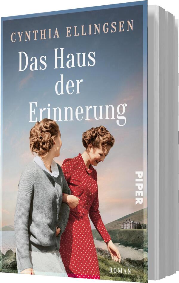 Das Buchcover zeigt zwei Frauen in zeitgenössischer Kleidung, die eng beieinander stehen und lächeln. Die Frau links trägt einen grauen Pullover, die rechte wählt ein rotes Kleid. Im Hintergrund erstreckt sich eine malerische Landschaft mit sanften Hügeln und einem historischen Gebäude. Der Himmel ist blau und scheint eine warme Atmosphäre zu vermitteln. Der Titel „Das Haus der Erinnerung“ ist in großen, weißen Buchstaben platziert, sowie der Autorenname „Cynthia Ellingsen“ oben in kleinerer Schrift. Unten rechts ist das Wort „ROMAN“ zu sehen.