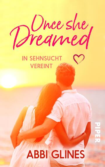 Das Buchcover zeigt ein romantisches Paar, das sich umarmt, während sie einem Sonnenuntergang am Strand zusehen. Die beiden sind von hinten sichtbar; die Frau trägt ein leichtes, helles Oberteil, der Mann ein weißes Hemd. Der Hintergrund ist in sanften Umtönen von Gelb und Pink gehalten, was eine warme, träumerische Atmosphäre schafft. Der Titel „Once she Dreamed“ ist in geschwungener, pinker Schrift gestaltet, während der Untertitel „in Sehnsucht vereint“ in einer schlichteren Schriftart darunter steht. Der Name der Autorin, Abbi Glines, ist ebenfalls in pinker Schrift am unteren Rand platziert.