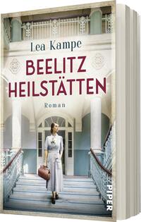 Das Buchcover zeigt eine Frau in historischer Kleidung, die auf einer Treppe der Beelitzer Heilstätten steht. Sie trägt eine Tasche und hat einen Strauß Blumen in der Hand. Der Hintergrund besteht aus weißen Wänden und dekorativen Säulen, die eine helle und freundliche Atmosphäre vermitteln. Der Titel „BEELITZ HEILSTÄTTEN“ steht in großen, burgunderroten Buchstaben, während der Autorenname „Lea Kampe“ darüber in einer eleganten Schriftart platziert ist. Unter dem Titel ist das Wort „Roman“ in kleinerer Schrift.