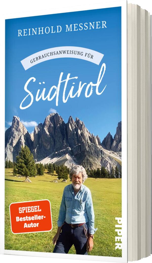 Das Buchcover zeigt eine malerische Landschaft mit majestätischen Bergen im Hintergrund. Im Vordergrund steht ein älterer Mann mit grauen Haaren, der freundlich in die Kamera lächelt. Der Himmel ist klar und blau. Der Titel „Gebrauchsanweisung für Südtirol“ ist in verspielter, weiße Schrift hervorgehoben und über dem Titel verläuft ein geschwungener Bogen. Oben ist der Autorennamen „Reinhold Messner“ in klaren, oberen Buchstaben platziert. Ein rotes Kästchen mit dem Text „SPIEGEL-Bestseller-Autor“ befindet sich am unteren Rand des Covers.