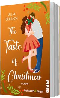 Das Buchcover zeigt einen warmen orangefarbenen Hintergrund mit weihnachtlichen grünen Zweigen und roten Beeren. Mittig ein Paar, das sich küssend umarmt, Gesichter hinter einem Geschenk verdeckt; Frau in rotem Kleid und Pumps, Mann in weißem Hemd, blauer Jeans und Sneakern. Titel „The Taste of Christmas“ in großer weißer, verschnörkelter Schrift, Autor „Julia Schuck“ oben links, darunter klein „Roman“. Stimmung: romantisch, festlich, verspielt.