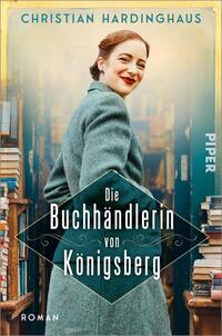 Das Buchcover zeigt eine lächelnde Frau mit einem lockeren Haarknoten, die in einem grünen Mantel vor einem Bücherregal steht. Im Hintergrund sind zahlreiche Bücher sichtbar, die eine einladende Atmosphäre schaffen. Der Titel „Die Buchhändlerin von Königsberg“ ist in eleganter, weißer Schrift auf einem schwarzen, geschweiften Schild abgebildet. Der Autor Christian Hardinghaus ist oben auf dem Cover in größerer Schrift platziert. Die Gesamtfarbgebung ist warm und harmonisch, mit einem leichten Retro-Feeling.