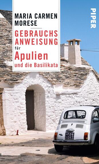 Das Buchcover zeigt ein weißes, traditionelles Gebäude mit einem charakteristischen rundem Dach in einer sonnigen Umgebung. Im Vordergrund steht ein klassisches, kleines Auto, das die italienische Atmosphäre verstärkt. Der Titel „Gebrauchsanweisung für Apulien und die Basilikata“ ist in kräftigen, roten Buchstaben platziert, während der Autorennamen Maria Carmen Morese in schwarzer Schrift darüber hervorgehoben wird. Der Verlagsname „PIPER“ ist in einem schlichten, weißen Schriftzug in der oberen rechten Ecke abgedruckt.