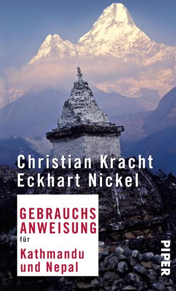 Das Buchcover zeigt ein eindrucksvolles Gebirgspanorama mit einem schneebedeckten Gipfel im Hintergrund, umgeben von sanften Bergen und einem klaren Himmel. Im Vordergrund erscheint eine traditionelle Stupa, die die Kultur Nepals symbolisiert. Der Titel „GEBRAUCHSANWEISUNG für Kathmandu und Nepal“ ist in rot und weiß hervorgehoben, während die Autorennamen Christian Kracht und Eckhart Nickel in weißer Schrift oberhalb des Titels stehen. Die Farbgebung vermittelt eine erdverbundene, inspirierende Atmosphäre.