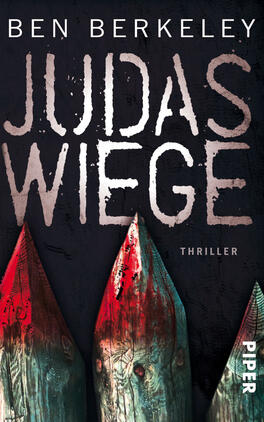 Das Buchcover zeigt den Titel „JUDAS WIEGE“ in großen, auffälligen Buchstaben, die teilweise verzerrt erscheinen und in einem dunklen Grauton gehalten sind. Der Untertitel „Thriller“ steht in kleineren, schlichten Schriftzeichen darunter. Im Hintergrund sind spitze, rot gefärbte Holztäfelchen zu sehen, die einen bedrohlichen Eindruck vermitteln. Der Hintergrund ist in dunklen, neutralen Farbtönen gehalten, was zur spannungsgeladenen Atmosphäre des Covers beiträgt. Der Name des Autors, Ben Berkeley, ist oberhalb des Titels platziert.