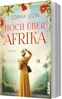 Das Buchcover zeigt eine rückwärtige Ansicht einer Frau in gelbem Kleid und Hut mit Umhängetasche, die in ein nebliges, grünes Tal mit Palmen blickt; ein kleiner Vogel fliegt vor der Szenerie. Oben rahmen rote Blumen und Blätter das Bild. Der Autorenname „Sophia Leon“ steht oben in schmaler Großschrift, der Titel HOCH ÜBER AFRIKA in großer roter Serifenschrift; Stimmung: nostalgisch und abenteuerlich.