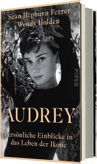 Das Buchcover zeigt ein schwarz-weißes Porträt von Audrey Hepburn, umgeben von blättrigen Pflanzen. Ihr ausdrucksvoller Blick ist zum Betrachter gerichtet. Der Titel „AUDREY“ ist groß und in elegantem, goldenen Schriftzug platziert, während der Untertitel „Persönliche Einblicke in das Leben der Ikone“ in kleinerer Schrift darunter steht. Die Autoren Sean Hepburn Ferrer und Wendy Holden sind im oberen Bereich des Covers genannt. Die Gesamtatmosphäre strahlt Eleganz und Nostalgie aus.