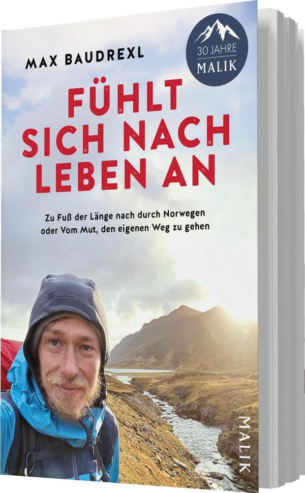 Das Buchcover zeigt einen Wanderer mit breitem Lächeln und einem blauen Kapuzenpullover, der auf einem schroffen Gelände steht. Die Farbpalette umfasst sanfte Schuhe, während der Himmel in leichten Blau- und Grautönen strahlt. Der Titel „FÜHLT SICH NACH LEBEN AN“ ist in markanter roter Schrift oben platziert, gefolgt vom Autorennamen Max Baudrex. Am oberen Rand befindet sich ein runder Hinweis „30 JAHRE MALIK“. Der Untertitel beschreibt die Reise durch Norwegen.