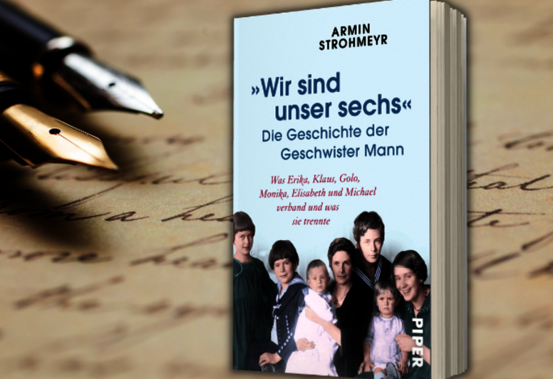 Armin Strohmeyrs „Wir sind unser sechs“ zu sehen vor handschriftlichem Text mit zwei Füllern