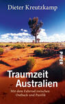 Das Buchcover zeigt eine weite australische Landschaft mit roten Sandböden und gesprenkeltem grünem Bewuchs. Im Hintergrund sind strahlend blaue Himmel mit wenigen weißen Wolken abgebildet. Der Titel „Traumzeit Australien“ ist in großer, weißer Schrift zentriert platziert, während der Untertitel „Mit dem Fahrrad zwischen Outback und Pazifik“ in kleinerer Schrift darunter steht. Oben ist der Name des Autors, Dieter Kreutzkamp, in charakteristischer Schrift zu sehen.