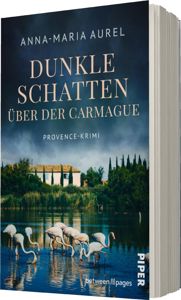 Das Buchcover zeigt eine ruhige Landschaft mit einem Gewässer im Vordergrund, in dem mehrere Flamingos stehen. Im Hintergrund erheben sich grüne Bäume und eine helle, mediterrane Villa vor einem bewölkten Himmel. Der Titel „Dunkle Schatten über der Carmague“ ist in großen, goldenen Buchstaben prominent platziert, während darunter der Zusatz „Provence-Krimi“ in einer kleineren Schriftart erscheint. Der Name der Autorin, „Anna-Maria Aurel“, steht oben auf dem Cover. Das Gesamtbild vermittelt eine geheimnisvolle und melancholische Atmosphäre.