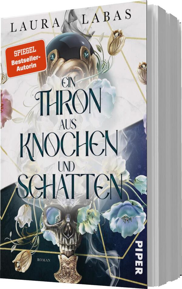 Das Buchcover zeigt einen mystischen Hintergrund in Blau-Tönen, der mit floralen Elementen in sanften Farben verziert ist. Im Zentrum befindet sich ein stilisierter Totenschädel, umgeben von zarten Blumen und einer goldenen Krone. Der Titel „Ein Thron aus Knochen und Schatten“ ist in einer eleganten, geschwungenen Schriftart in Schwarz und Weiß gestaltet. Oben links prangt ein rotes Etikett mit dem Text „SPIEGEL Bestseller-Autorin“. Der Verlag ist am unteren Rand in schlichter typografischer Schrift aufgeführt.