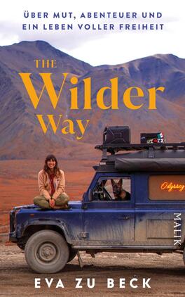 The Wilder Way Das Buchcover zeigt eine Frau mit braunen Haaren, die lächelnd auf einem geländegängigen Fahrzeug sitzt, während ein Hund auf der Fahrerseite sichtbar ist. Der Hintergrund zeigt eine beeindruckende Berglandschaft in warmen Erdtönen. Der Titel „THE Wilder Way“ ist in großen, gelben Buchstaben oberhalb der Abbildung platziert, begleitet von dem Untertitel „Über Mut, Abenteuer und ein Leben voller Freiheit“ in kleinerer Schrift. Der Name der Autorin, „Eva zu Beck“, steht am rechten unteren Rand in weißer Schrift.