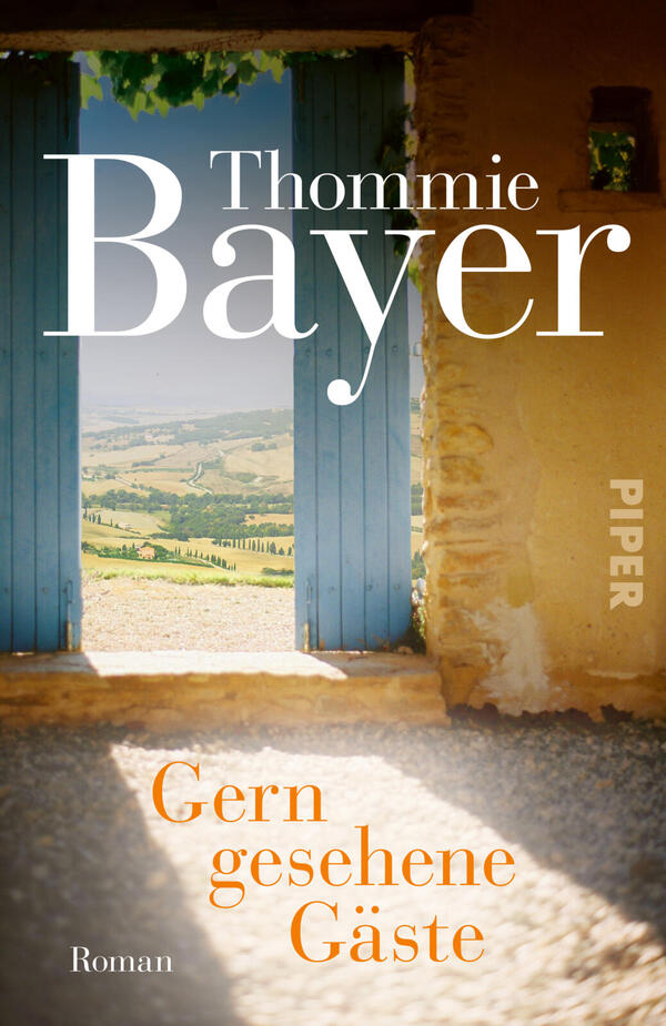 Das Buchcover zeigt einen offenen, blauen Holztorrahmen, der auf eine sonnige, hügelige Landschaft mit Feldern und Zypressen blickt; rechts ist eine sonnengebleichte, sandfarbene Mauer mit Fensteröffnung sichtbar. Oben großer weißer Autorname „Thommie Bayer“, unten mittig in orange der Titel „Gern gesehene Gäste“, links unten in kleiner weißer Schrift „Roman“. Atmosphäre: warm, einladend, sommerlich.