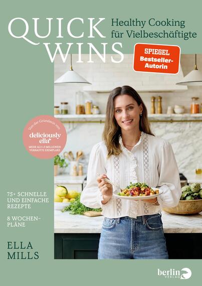 Das Buchcover zeigt eine Frau, die in einer hellen, modernen Küche steht und einen Teller mit buntem Gemüse hält. Der Hintergrund ist in sanften Grüntönen gehalten. Oben links befindet sich der Titel „QUICK WINS“ in großen, weißen Buchstaben, unter dem der Untertitel „Healthy Cooking für Vielbeschäftigte“ in kleinerer Schrift steht. Unten rechts ist der Name „ELLA MILLS“ in dunklerer Schrift sowie ein pinker Button mit dem Text „deliciously ella“. Die Atmosphäre ist einladend und frisch.