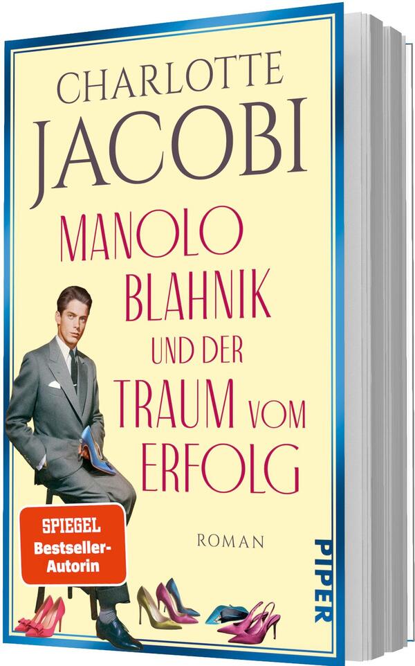 Das Buchcover zeigt einen cremefarbenen Hintergrund mit großem blauen Autorennamen „CHARLOTTE JACOBI“ oben und dem roten Titel „MANOLO BLAHNIK und der Traum vom Erfolg“ darunter. Im Vordergrund ein blauer, hochhackiger Damenschuh mit funkelnder Verzierung; rechts ein Mann im grauen Anzug, der einen Schuh in der Hand präsentiert. Unten links ein oranger quadratischer Button mit weißer Aufschrift „SPIEGEL Bestseller-Autorin“. Kleiner Hinweis „ROMAN“ unter dem Titel.
