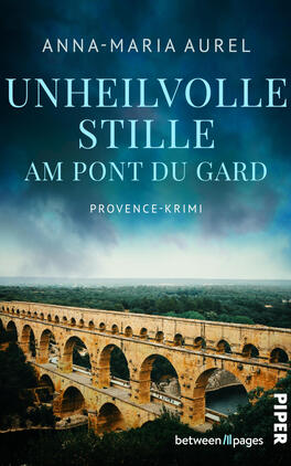 Das Buchcover zeigt eine dramatische Ansicht des römischen Aquädukts Pont du Gard in warmem Ockerton vor einem dunklen, sturmblauen Himmel mit Nebelschleier. Titel „Unheilvolle Stille am Pont du Gard“ erscheint groß, hellblau, in versaler Serifenschrift; darunter klein die Genrebezeichnung „Provence‑Krimi“. Oben steht die Autorin Anna‑Maria Aurel in weißer, schlichter Schrift. Die Stimmung ist bedrohlich und melancholisch.
