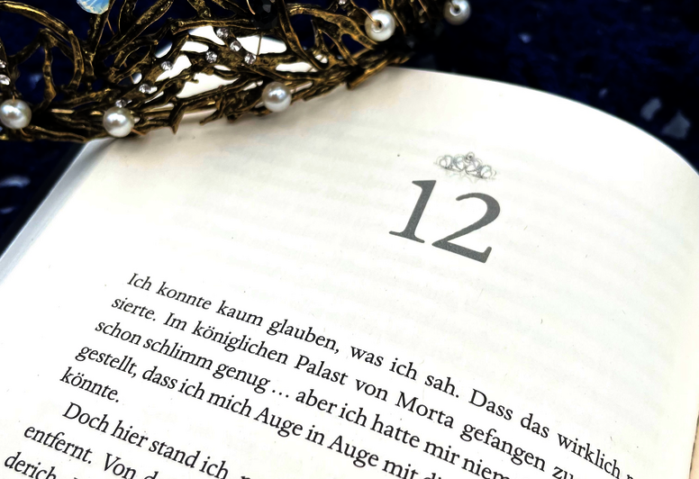 aufgeschlagenes Buch, auf dem ein Diadem liegt