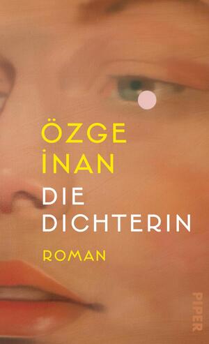 Das Buchcover zeigt ein enges, gemaltes Porträt einer weiblichen Gesichtshälfte in warmen Pfirsich-, Rosen- und Hauttönen, mit einem grünen Auge und einem kleinen rosa Punkt neben dem Auge. Der Autorenname ÖZGE İNAN ist groß in gelber Grotesk gesetzt, der Titel „DIE DICHTERIN“ erscheint in weißer Versal-Grotesk, darunter in gelb das Wort „ROMAN“. Die Stimmung ist intim und malerisch.