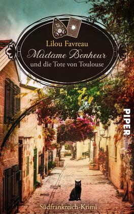 Das Buchcover zeigt eine malerische Gasse in Toulouse, gesäumt von historischen Gebäuden mit bunten Fensterläden. In der Mitte des Covers stehen in einer eleganten Schrift der Titel „Madame Bonheur und die Tote von Toulouse“ sowie der Autor Lilou Favreau, umrahmt von einer dekorativen, ovalen Grafik. Im Vordergrund sitzt ein schwarzer Kater vor blühenden Pflanzen, die lebendige Farben wie Grün und Pink aufweisen. Der Verlagsname „PIPER“ erscheint in weißer Schrift am rechten Rand.