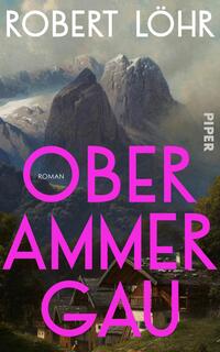 Das Buchcover zeigt eine eindrucksvolle alpine Landschaft mit markanten Berggipfeln im Hintergrund. Im Vordergrund sind traditionsreiche Holzhäuser zu sehen. Der Titel „OBERAMMERGAU“ ist in großen, leuchtend pinken Buchstaben gestaltet, während darunter das Wort „ROMAN“ in einer schmaleren, eleganten Schrift steht. Der Autor „ROBERT LÖHR“ ist in weißen, klaren Buchstaben am oberen Rand platziert. Die Farbgebung und Komposition vermitteln eine einladende, zugleich mystische Atmosphäre.