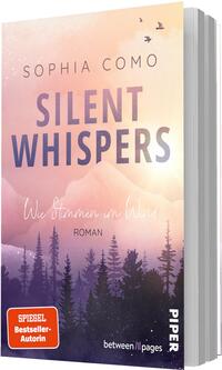 Das Buchcover zeigt einen sanft verlaufenden Himmel in Pastelltönen (Pfirsich, Rosa, Hellgelb) über violetten Berg- und Nadelwald-Silhouetten; drei Vögel fliegen rechts oben. Oben steht der Autorenname „Sophia Como“, der Titel „Silent Whispers“ in großer, fetter, violett verlaufender Grotesk, darunter in handschriftlicher Kursivschrift der Untertitel „Wie Stimmen im Wind“ und die Genreangabe „Roman“. Stimmung ruhig, melancholisch, verträumt.