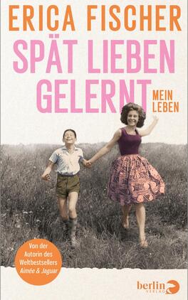 Das Buchcover zeigt zwei Mädchen, die Hand in Hand auf einer Wiese laufen. Die linke Figur trägt ein kariertes Hemd und Shorts, die rechte Figur ein ärmelloses, bläuliches Oberteil und einen Rock mit floralen Mustern. Der Hintergrund ist unscharf und zeigt eine gefühlvolle, nostalgische Landschaft. Der Titel „SPÄT LIEBEN GELERNT“ ist in auffälligen, rosa Buchstaben geschrieben, während der Untertitel „mein Leben“ in einer schlichteren Schriftart steht. Oben rechts ist der Name der Autorin „Erica Fischer“ in orange zu sehen. Unten steht der Hinweis „Von der Autorin des Weltbestsellers Aimee & Jaguar“.