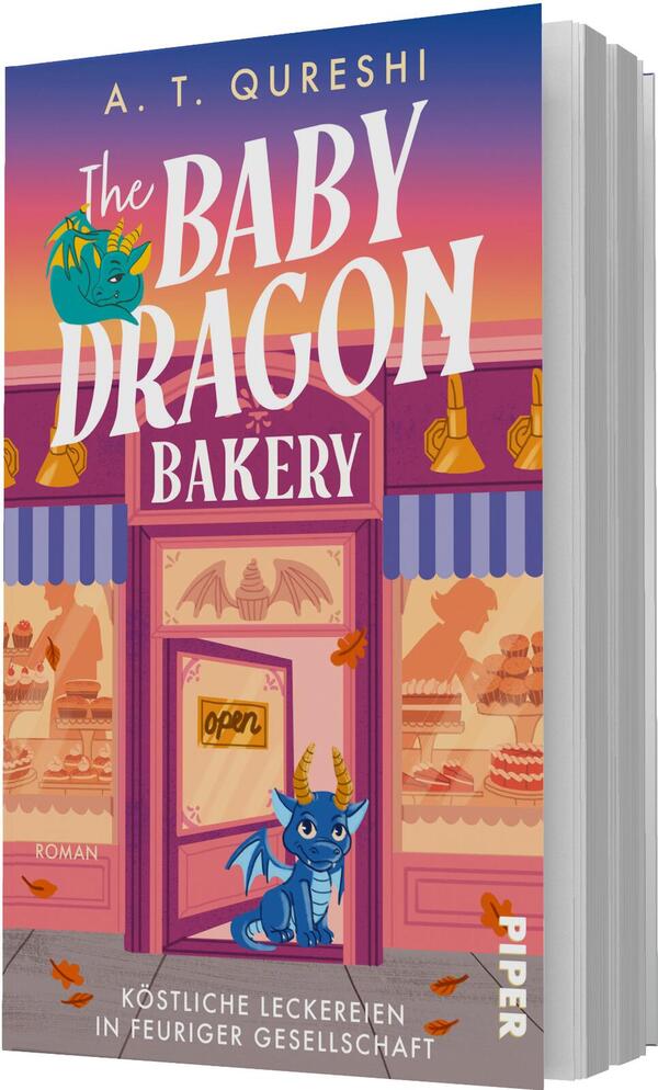 Das Buchcover zeigt eine verspielte, rosa-violette Bäckerei-Fassade vor einem orange-violetten Himmel. Groß oben steht der Autorenname A. T. Qureshi in Gelb, der Titel „The Baby Dragon Bakery“ in großer weißer, verspielter Serifschrift. Im Mittelpunkt sitzt ein blauer Babydrache in der Tür; im Fenster sind Kuchen und warme Lampen zu sehen. Ein kleines Schild im Türfenster zeigt „open“. Unter dem Bild steht der Untertitel „Köstliche Leckereien in feuriger Gesellschaft“.