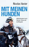 Das Buchcover zeigt einen grinsenden Mann mit dunklem Bart in einer winterlichen Landschaft, umgeben von mehreren Hunden. Die Tiere sind meist in Grau- und Schwarztönen gehalten, während der Mann eine warme, helle Jacke trägt. Der Titel „MIT MEINEN HUNDEN“ ist in großen, hellblauen Buchstaben prominent platziert, unter dem sich der Untertitel „6000 Kilometer durch Sibirien, China und die Mongolei“ in schlichter Schrift befindet. Der Autorname „Nicolas Vanier“ steht oben auf dem Cover in dezentem Schwarz.