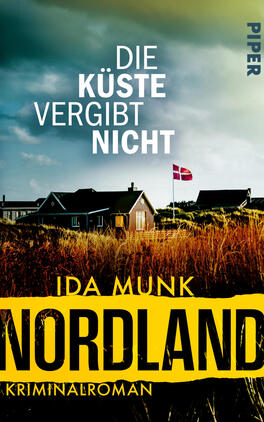 Das Buchcover zeigt eine düstere Küstenlandschaft mit stürmischem blau-grünem Himmel, vereinzelten niedrigen Häusern, einem Dänemark-Fähnchen auf einer Flagge und goldbraunen Strandgräsern im Vordergrund. Oben steht der Titel „Die Küste vergibt nicht“ in weißer Großschrift. Darunter erscheint der Autorenname „Ida Munk“ und ein breiter gelber Balken mit großem schwarzen Schriftzug „NORDLAND“ sowie dem kleinen Hinweis „Kriminalroman“. Atmosphäre: rau, spannungsgeladen.