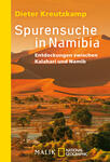 Das Buchcover zeigt eine beeindruckende Wüstenlandschaft Namibias mit weitläufigen Sanddünen unter einem strahlend blauen Himmel. Im Vordergrund sind grüne Pflanzen und Bäume sichtbar. Der Titel „Spurensuche in Namibia“ ist in großen, weißen Buchstaben geschrieben, während der Untertitel „Entdeckungen zwischen Kalahari und Namib“ kleiner und ebenfalls in Weiß gehalten ist. Der Autorennamen „Dieter Kreutzkamp“ steht über dem Titel. Die Farbgestaltung vermittelt eine warme und einladende Atmosphäre.