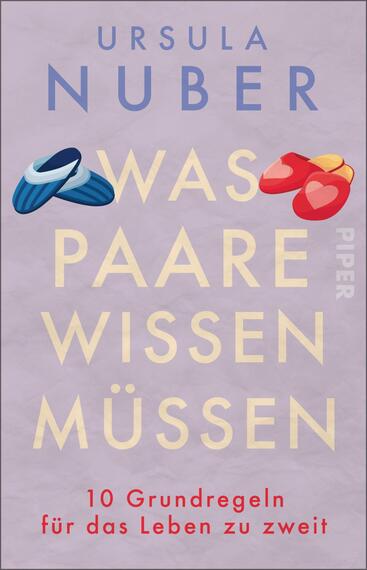 Das Buchcover zeigt einen sanften lilafarbenen Hintergrund. Darauf sind die Worte „Was Paare wissen müssen“ in großen, gelben Buchstaben angeordnet. Oben steht der Name „Ursula Nuber“ in hellblauer Schrift. Neben dem Titel befinden sich zwei stilisierte Symbole: ein blaues Paar Hausschuhe und ein rotes Herz. Am unteren Rand des Covers steht der Hinweis „10 Grundregeln für das Leben zu zweit“. Die Gesamtatmosphäre vermittelt eine freundliche und einladende Stimmung.