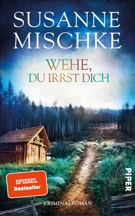 Das Buchcover zeigt eine düstere Waldlandschaft mit einem verschwommenen, schmalen Weg, der zu einer einsamen Hütte führt. Der Himmel ist in sanften Blau- und Türkistönen gehalten, die eine geheimnisvolle Atmosphäre erzeugen. Der Titel „WEHE, DU IRRST DICH“ ist prominent in eleganter, grüner Schrift platziert. Darüber steht der Name der Autorin, Susanne Mischke, in größeren, weißen Buchstaben. Ein rotes Label mit dem Text „SPIEGEL Bestseller“ hebt sich am unteren linken Rand hervor und verdeutlicht den Erfolg des Buches.