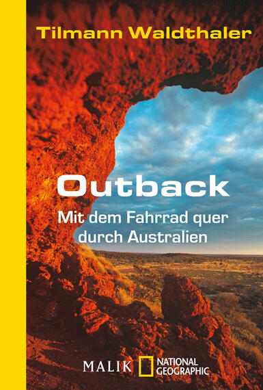Das Buchcover zeigt eine beeindruckende Rocklandschaft im Outback Australien, mit leuchtend roten Felsen und einem klaren blauen Himmel. Der Titel „Outback“ ist in großen, weißen Buchstaben zentral platziert, darunter folgt der Untertitel „Mit dem Fahrrad quer durch Australien“ in kleinerer Schriftgröße. Der Name des Autors, Tilmann Waldthaler, steht ebenfalls auf dem Cover. Die Farbkombination aus Erdtönen und Blau vermittelt eine abenteuerliche und einladende Atmosphäre.