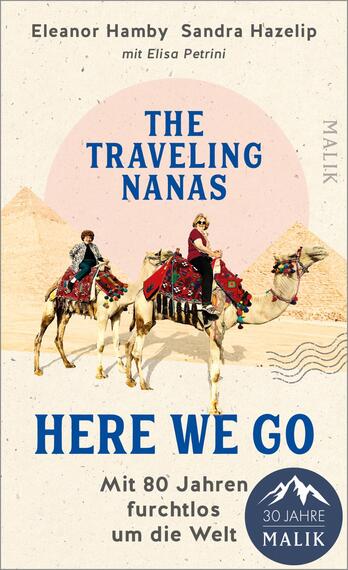 Das Buchcover zeigt zwei Reiterinnen auf Kamelen in einer Wüstenlandschaft, umgeben von Pyramiden. Die Farben sind überwiegend hell mit sanften Rosa- und Beigetönen, die eine warme Atmosphäre vermitteln. Der Titel „THE TRAVELING NANAS“ ist prominent in blauer Blockschrift platziert, während darunter „HERE WE GO“ in einer dynamischen Schriftart in dunklem Blau zu sehen ist. Unter dem Haupttitel steht der Untertitel „Mit 80 Jahren furchtlos um die Welt“. Angaben zu den Autorinnen Eleanor Hamby und Sandra Hazelip sind ebenfalls im oberen Bereich des Covers platziert.