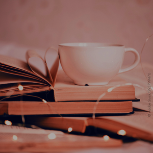 Tasse auf einem Stapel aufgeschlagener Bücher