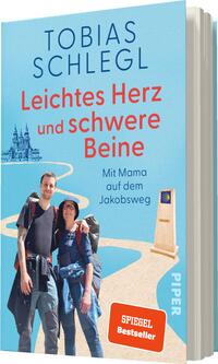 Das Buchcover zeigt ein hellblaues Design mit einer Illustration eines symbolischen Weges, der sich durch die Landschaft schlängelt. Oben steht der Titel „Leichtes Herz und schwere Beine“ in großer, roter Schrift. Darunter sind die Worte „Mit Mama auf dem Jakobsweg“ in kleinerer Schrift. Im Vordergrund sind zwei Personen abgebildet, die Wanderausrüstung tragen und sich freundlich umarmen. Links im Hintergrund sind stilisierte Gebäude zu sehen. Das Cover enthält das „SPIEGEL Bestseller“-Logo.