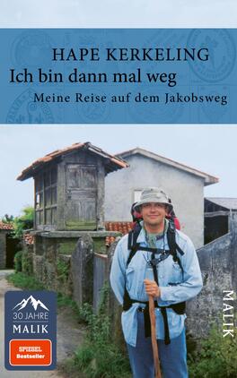Das Buchcover zeigt einen lächelnden Hape Kerkeling, der mit einem Rucksack und Wanderausrüstung auf einem Weg steht. Im Hintergrund sind traditionelle Gebäude und grüne Landschaften zu sehen. Der obere Teil des Covers ist in einem hellen Blau gehalten, darüber steht der Titel „Ich bin dann mal weg“ in großer, schwarzer Schrift. Darunter steht der Untertitel „Meine Reise auf dem Jakobsweg“ in kleinerer Schrift. In der unteren linken Ecke befindet sich das Logo „30 Jahre Malik“.