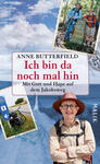Das Buchcover zeigt eine Collage aus Fotografien, die eine Wanderung auf dem Jakobsweg darstellen. Im Vordergrund steht eine lächelnde Person mit Brille und Hut, die eine fröhliche, aktive Ausstrahlung hat. Darüber steht der Titel „Ich bin da noch mal hin“ in auffälliger roter Schrift, gefolgt vom Untertitel „Mit Gott und Hape auf dem Jakobsweg“. Der Hintergrund ist in sanften Blau- und Grüntönen gehalten, während die angrenzenden Bilder Wanderzeichen und eine Karte zeigen, die das Thema der Reise unterstreichen. Der Name der Autorin, Anne Butterfield, steht oben auf dem Cover.