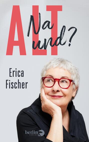 Das Buchcover zeigt eine lächelnde ältere Frau mit kurzen, grauen Haaren und einer dunklen Bluse. Sie trägt rote Brille und stützt ihr Kinn mit der Hand. Über ihr steht in großen, kräftigen roten Buchstaben „ALT“, daneben in geschwungener Schrift „Na und?“. Der Name der Autorin, Erica Fischer, ist in schwarzer Schrift am unteren Rand platziert. Der Hintergrund ist neutral grau, was eine freundliche und offene Atmosphäre vermittelt.
