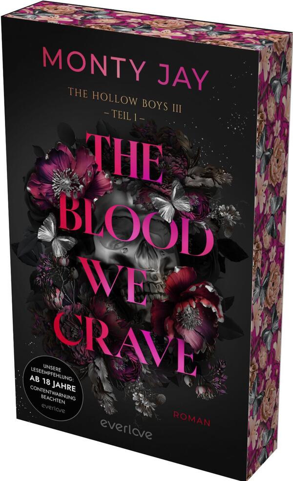 Das Buchcover zeigt ein dunkles, schwarzes Layout mit einem zentralen, teilweise verdeckten Totenschädel, umwoben von tiefrosa bis blutroten Blüten und silbrig schimmernden Schmetterlingen. Der Titel „THE BLOOD WE CRAVE“ steht groß, fett und in knalligem Pink, darüber der Autorname „MONTY JAY“ in kleinerer Großschrift; darüber schmale Zeile „THE HOLLOW BOYS III – TEIL I“. Unten links ein Rundbutton mit dem Text „UNSERE LESEEMPFEHLUNG: AB 18 JAHRE CONTENTWARNUNG BEACHTEN“.