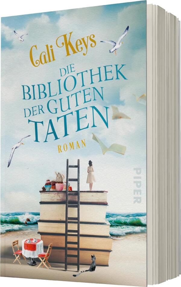 Das Buchcover zeigt einen sanften, blauen Himmel mit weißen Wolken und fliegenden Möwen. Im Vordergrund erhebt sich ein großer Bücherstapel, der als Treppe dient, mit einer Leiter, die an die obersten Bücher anlehnt. Ein kleiner runder Tisch mit einem Stuhl steht daneben, während im Hintergrund der Strand und das Meer sichtbar sind. Der Titel „Die Bibliothek der guten Taten“ ist in auffälligem Türkis gehalten, und der Name „Cali Keys“ in eleganter, goldener Schrift darüber. Der Schriftzug „Roman“ ist ebenfalls prominent platziert.