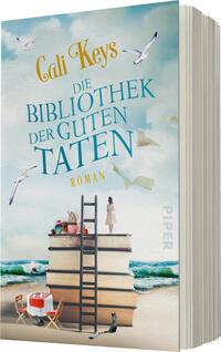 Das Buchcover zeigt einen sanften, blauen Himmel mit weißen Wolken und fliegenden Möwen. Im Vordergrund erhebt sich ein großer Bücherstapel, der als Treppe dient, mit einer Leiter, die an die obersten Bücher anlehnt. Ein kleiner runder Tisch mit einem Stuhl steht daneben, während im Hintergrund der Strand und das Meer sichtbar sind. Der Titel „Die Bibliothek der guten Taten“ ist in auffälligem Türkis gehalten, und der Name „Cali Keys“ in eleganter, goldener Schrift darüber. Der Schriftzug „Roman“ ist ebenfalls prominent platziert.
